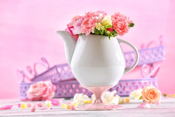 Composición con hermosas flores de primavera en tetera sobre fondo rosa claro —  Fotos de Stock