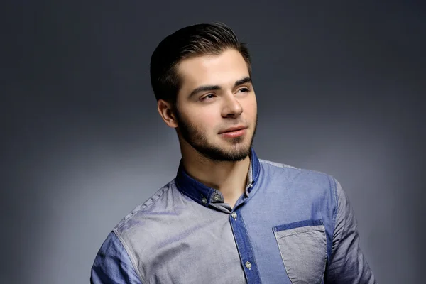 Portret van een jonge man in blauw shirt op grijze achtergrond — Stockfoto