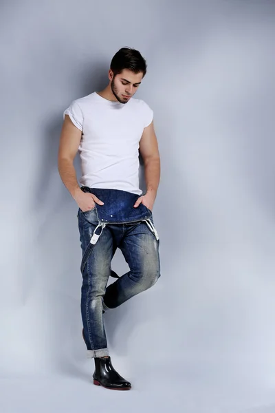 灰色の背景にジーンズのつなぎ服の男 — ストック写真
