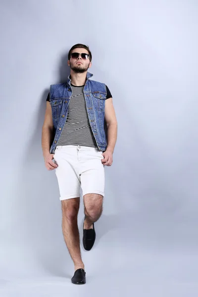 Uomo in pantaloncini bianchi e gilet jeans su sfondo grigio — Foto Stock