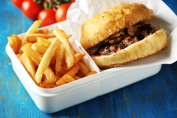 Νόστιμο burger και πατάτες τηγανιτές σε ξύλινο τραπέζι φόντο ανθυγιεινών τροφίμων ιδέα — Φωτογραφία Αρχείου