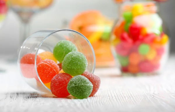 Coloridos caramelos en frascos sobre la mesa sobre fondo claro — Foto de Stock