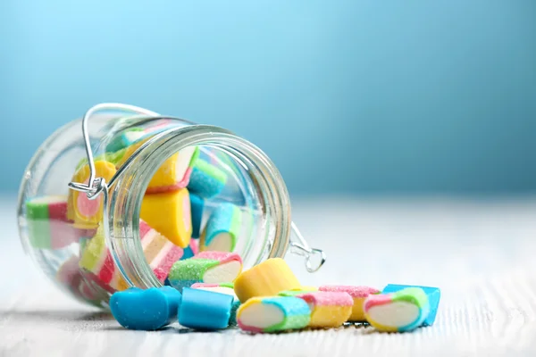 Colorful candies in jar on table on blue background — Stock Photo, Image