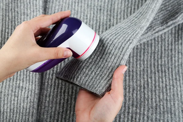 Kobiece ręce z wełny golarki na tle sweter wełny — Zdjęcie stockowe