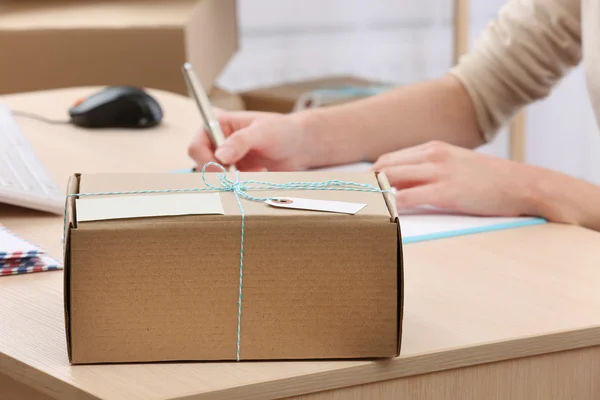 Caja de cartón en el lugar de trabajo en la oficina de correos — Foto de Stock