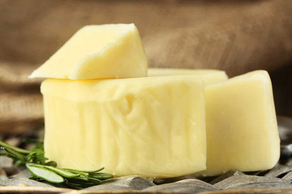 Cheese on wicker tray and sackcloth, closeup — Stock Photo, Image