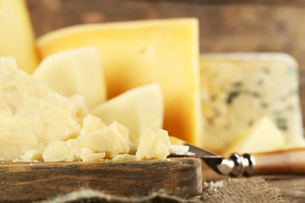 Diferentes tipos de queijo na placa de corte de madeira, close-up — Fotografia de Stock