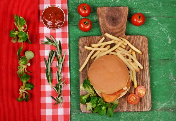 Hamburger, frites et légumes sur table en bois — Photo