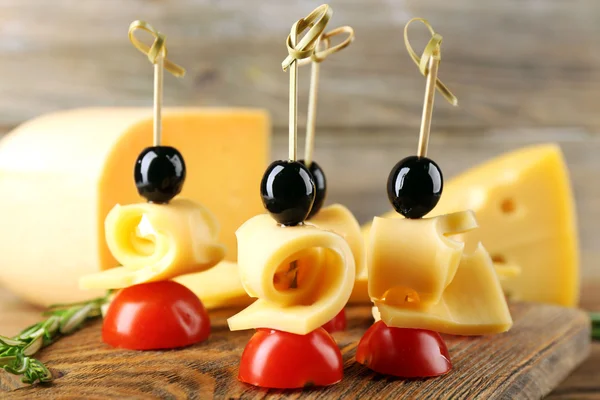 Сырные канапе с помидорами черри и оливками на деревянном фоне — стоковое фото