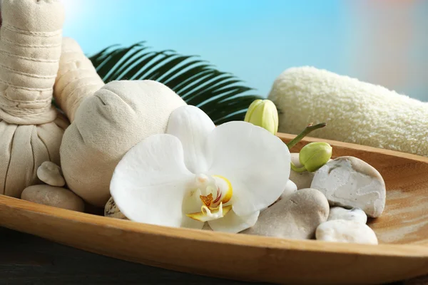 Stillleben mit schön blühender Orchideenblume, Wellnessbehandlung in Schale, auf Holztisch, auf hellem Hintergrund — Stockfoto