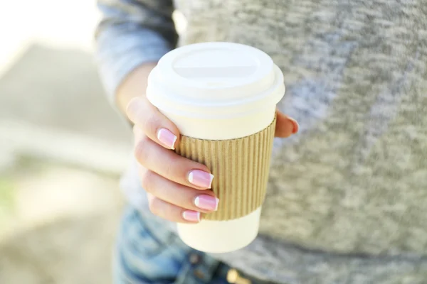 Kvinnlig hand med papper kopp kaffe utomhus, närbild — Stockfoto