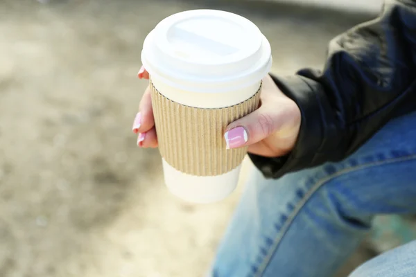 Женская рука с бумажной чашкой кофе на открытом воздухе, крупным планом — стоковое фото