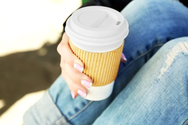 Female hand with paper cup of coffee outdoors, closeup — Stock Photo, Image