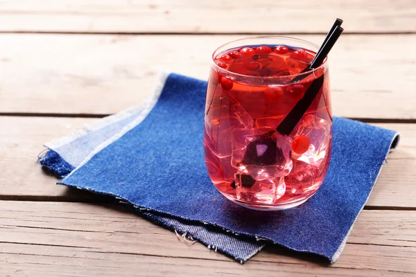 Vaso de compota con grosella roja sobre mesa de madera con tela vaquera, primer plano — Foto de Stock