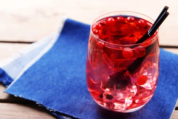 Glass of compote with red currant on wooden table with jeans cloth, closeup — Stock Photo, Image