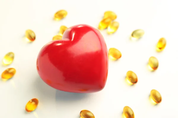 Červené srdce a olej z tresčích jater, izolované na bílém — Stock fotografie