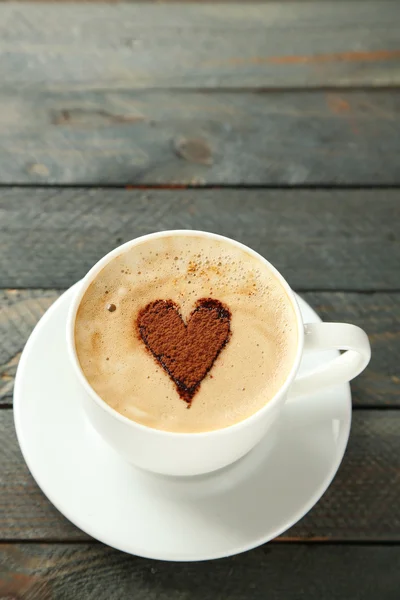 Kopje cappuccino met hart van cacao op houten tafel — Stockfoto