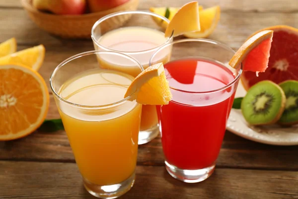 Fresh juices with fruits on wooden table — Stock Photo, Image