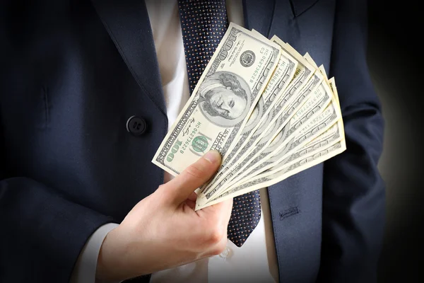 Empresário com dólares em mãos em fundo escuro — Fotografia de Stock
