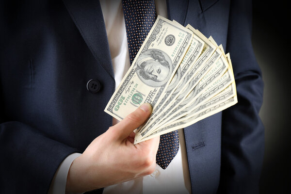Businessman with dollars in hands on dark background