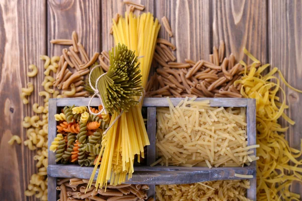 Different types of pasta in box on wooden background — Stock Photo, Image