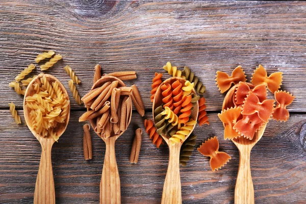 Различные виды макарон в ложках на деревянном фоне — стоковое фото