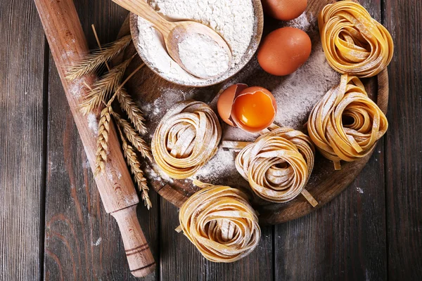 Pasta casera cruda e ingredientes para pasta sobre fondo de madera —  Fotos de Stock