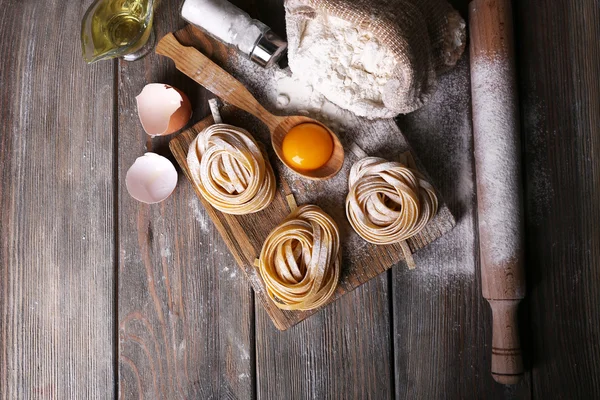 Pasta mentah buatan sendiri dan bahan-bahan untuk pasta pada latar belakang kayu — Stok Foto