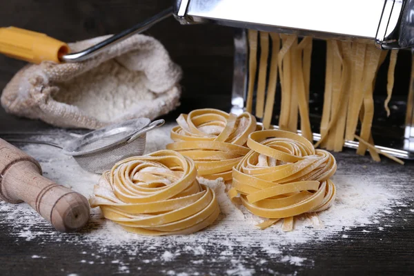 Metall pasta maker maskin och ingredienser för pasta på trä bakgrund — Stockfoto