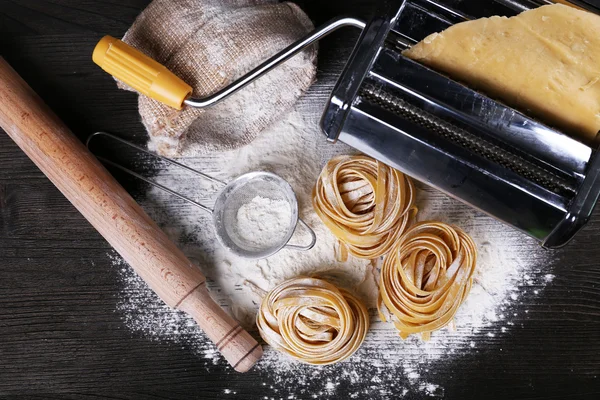 Metal pasta maker machine and ingredients for pasta on wooden background — Stock Photo, Image