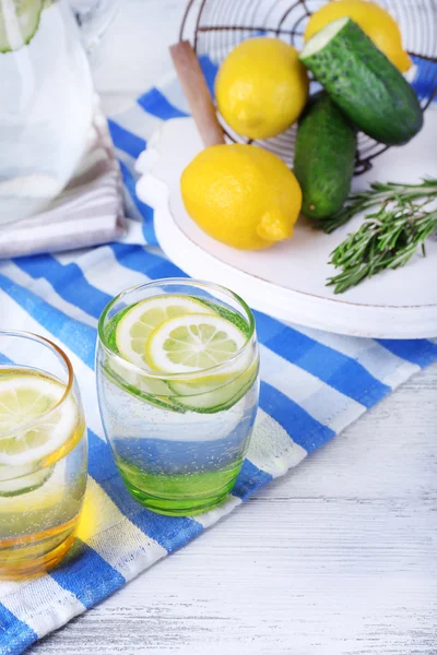 Свіжа вода з лимоном і огірком в скляному посуді на дерев'яному столі, крупним планом — стокове фото