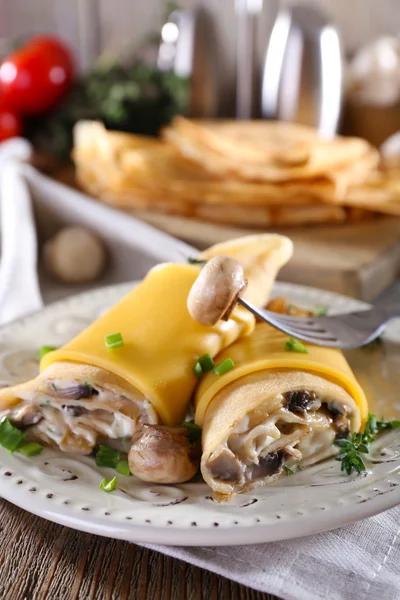 Pancakes with creamy mushrooms in plate on wooden table, closeup — Stock Photo, Image