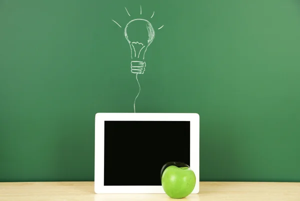 Tablet on table, on green blackboard background — Stock Photo, Image