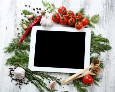 Taze otlar, domates ve baharat ahşap arka plan üzerinde dijital tablet