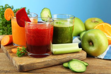 Karışım-in mavi zemin üzerine ahşap masa üzerinde cam şişelerde sağlıklı taze sıkılmış meyve suları