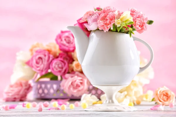 Composição com belas flores de primavera em bule de chá no fundo rosa claro — Fotografia de Stock