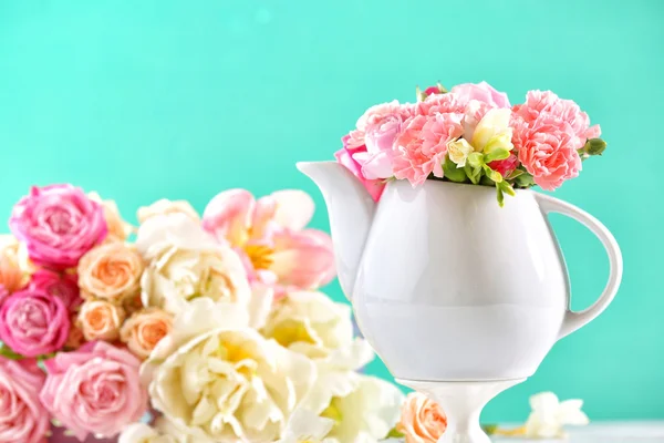 Kompozycja piękna wiosna kwiaty w czajnik na światło niebieskie tło — Zdjęcie stockowe