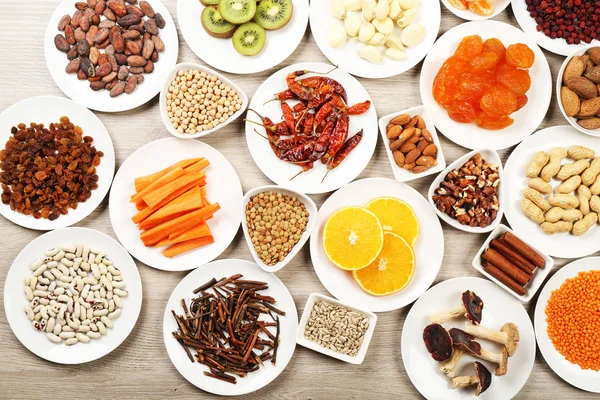 Different products on saucers on wooden table, top view — Stock Photo, Image