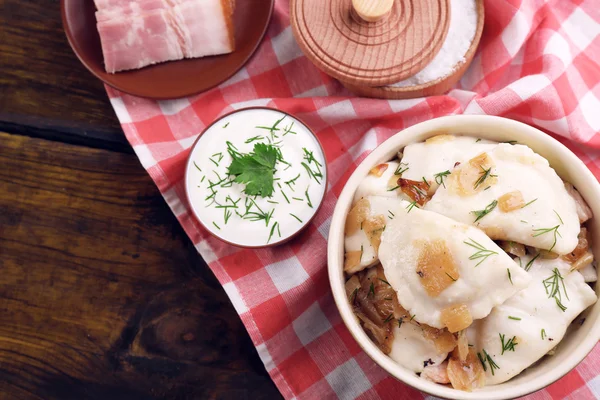 Tasty dumplings with fried onion in brown bowl, on wooden background — Stock Photo, Image