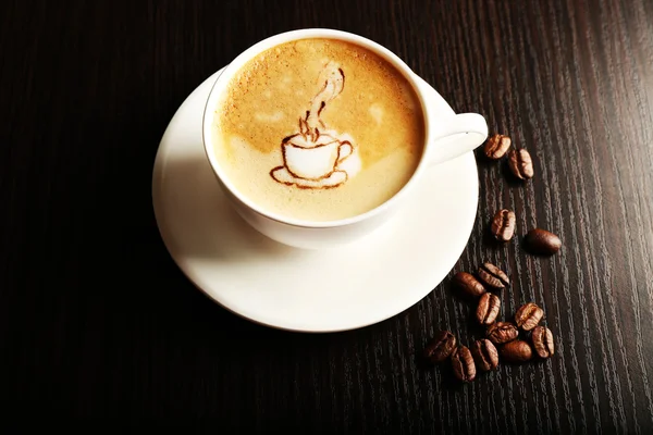 Cup of latte art coffee with beans on wooden background — Stock Photo, Image