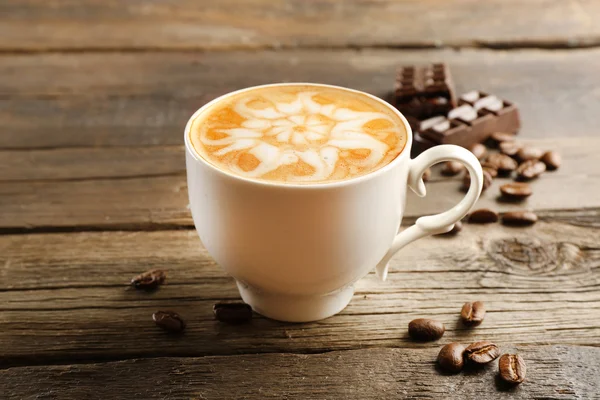 Filiżanka do kawy latte art z ziaren i czekolady na drewniane tła — Zdjęcie stockowe