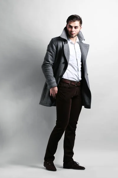 Young man in coat on gray background — Stock Photo, Image