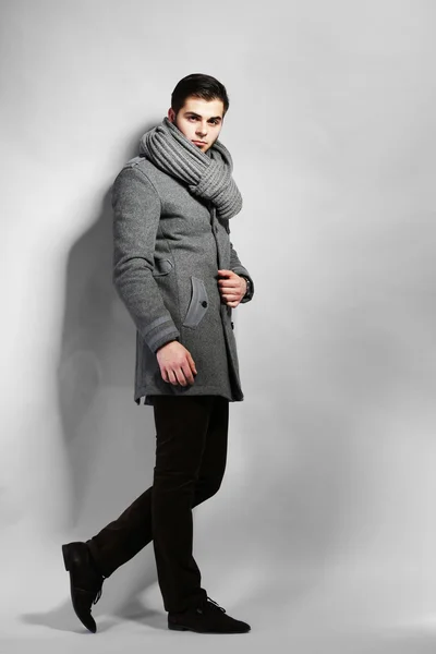 Jovem de casaco sobre fundo cinza — Fotografia de Stock