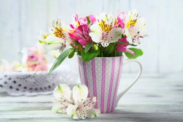 Красивые цветы в чашке, на деревянном фоне — стоковое фото