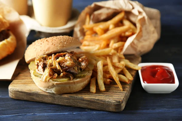 Hamburger savoureux et frites sur assiette, sur fond de table en bois. Concept d'aliments malsains — Photo