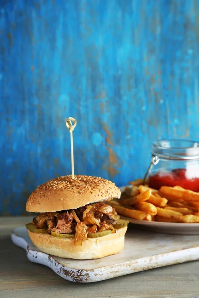 Tasty sandwich on cutting board, on color wooden background. Unhealthy food concept — Stock Photo, Image