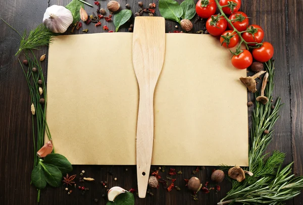 Livro de receitas aberto com ervas frescas, tomates e especiarias em fundo de madeira — Fotografia de Stock