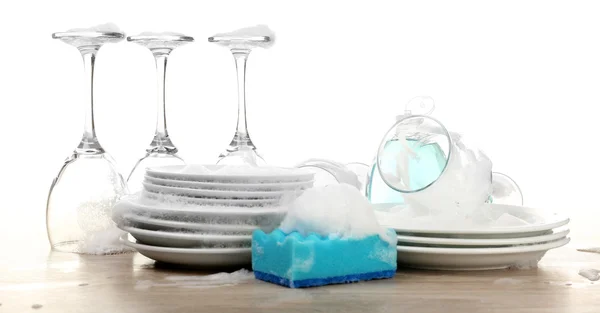 Dishes in foam with gloves and wisp on table isolated on white — Stock Photo, Image
