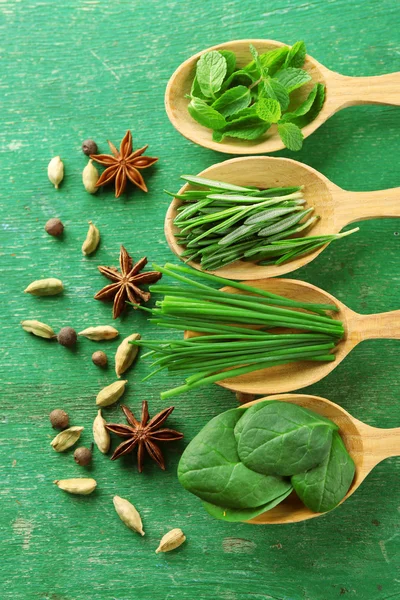 Wooden spoons with fresh herbs and spices on wooden background — Stock Photo, Image