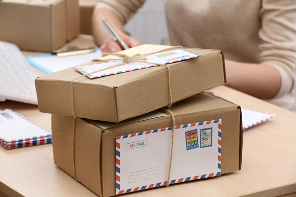 Cardboard boxes on work place in post office Stock Photo by ©belchonock